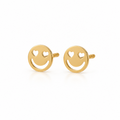 Gold stud earrings shaped like smiley faces with heart-shaped cutout eyes. Minimal gift for her under Rs. 15,000