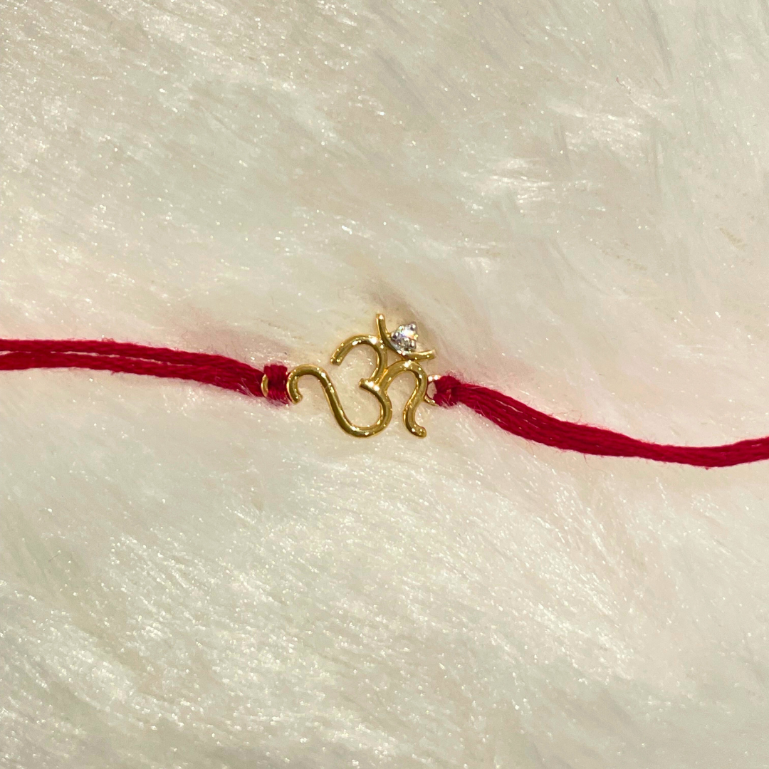Om Rakhi in 18kt gold with a natural diamond, tied on a red thread—symbolizing divine protection and perfect for Raksha Bandhan gifting for brother under Rs. 15,000!