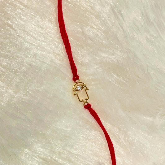 Hamsa Rakhi in 18kt gold with a natural diamond, tied on a red thread—symbolizing protection, love, and timeless gifting under Rs. 15,000!