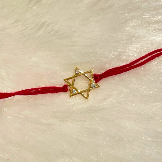 Star-shaped gold rakhi with natural diamond, tied on a red thread—crafted in 18kt gold for a meaningful Raksha Bandhan with your brother under Rs. 15,000!