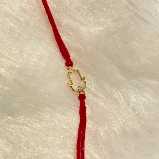 Amulet Rakhi in 18kt gold with a natural diamond, featuring a protective hand charm on red thread—perfect for Raksha Bandhan gifting under Rs. 15,000!