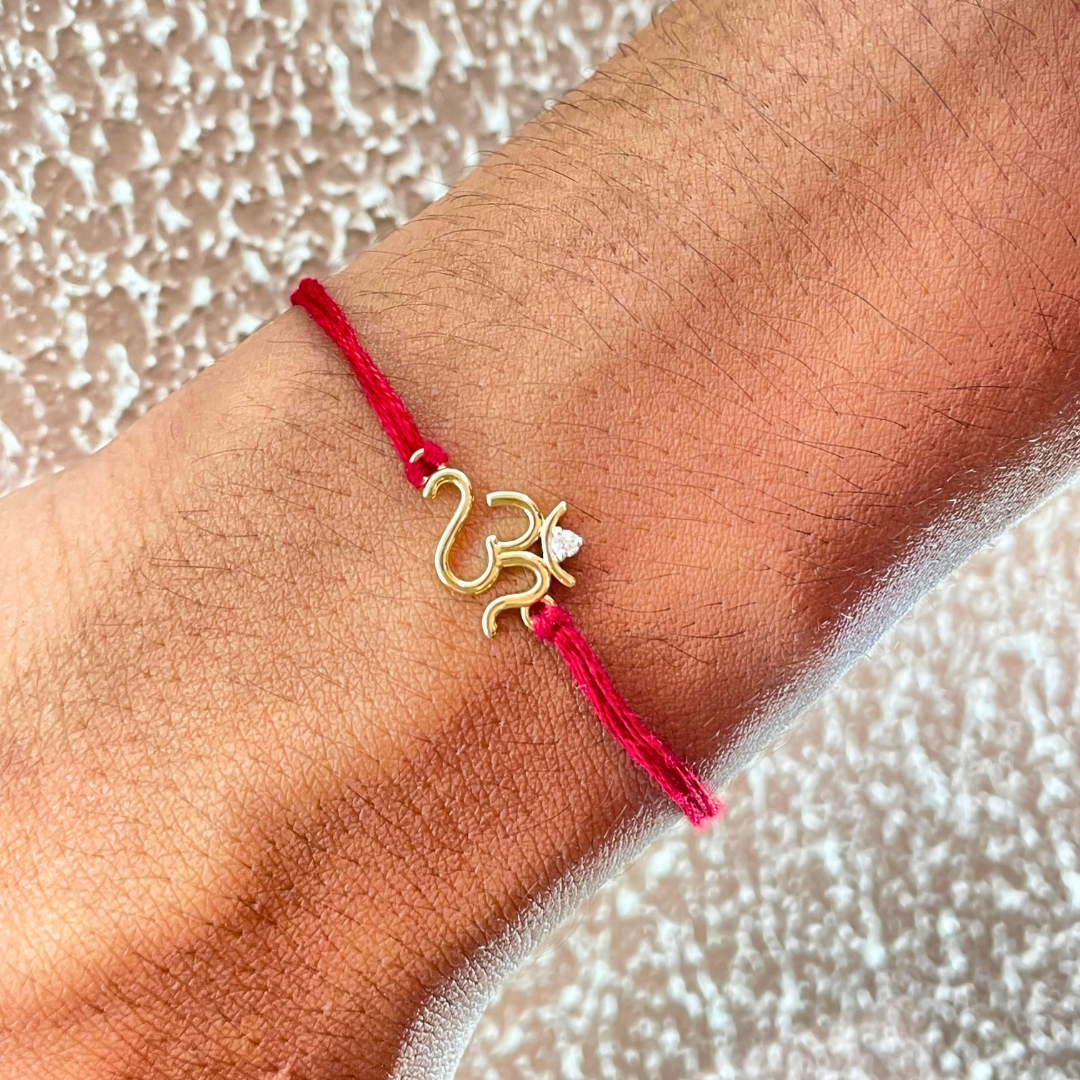 Om Rakhi in 18kt gold with a natural diamond, tied on a red thread—symbolizing divine protection and perfect for Raksha Bandhan gifting for brother under Rs. 15,000!