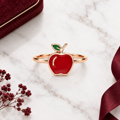 Rose gold ring with a glossy red enamel apple charm and a green leaf detail. Cute and minimal gifts for kids under Rs. 15,000