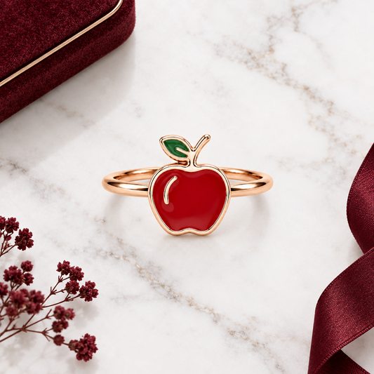 Rose gold ring with a glossy red enamel apple charm and a green leaf detail. Cute and minimal gifts for kids under Rs. 15,000