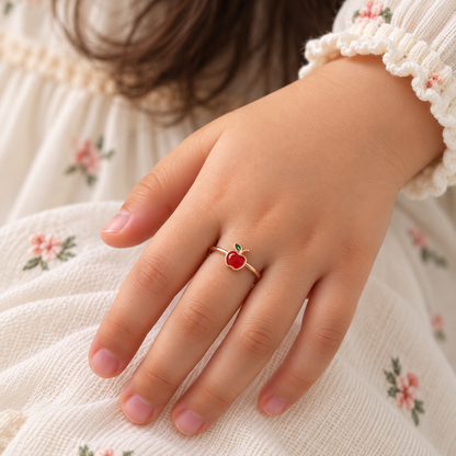 Rose gold ring with a glossy red enamel apple charm and a green leaf detail. Cute and minimal gifts for kids under Rs. 15,000