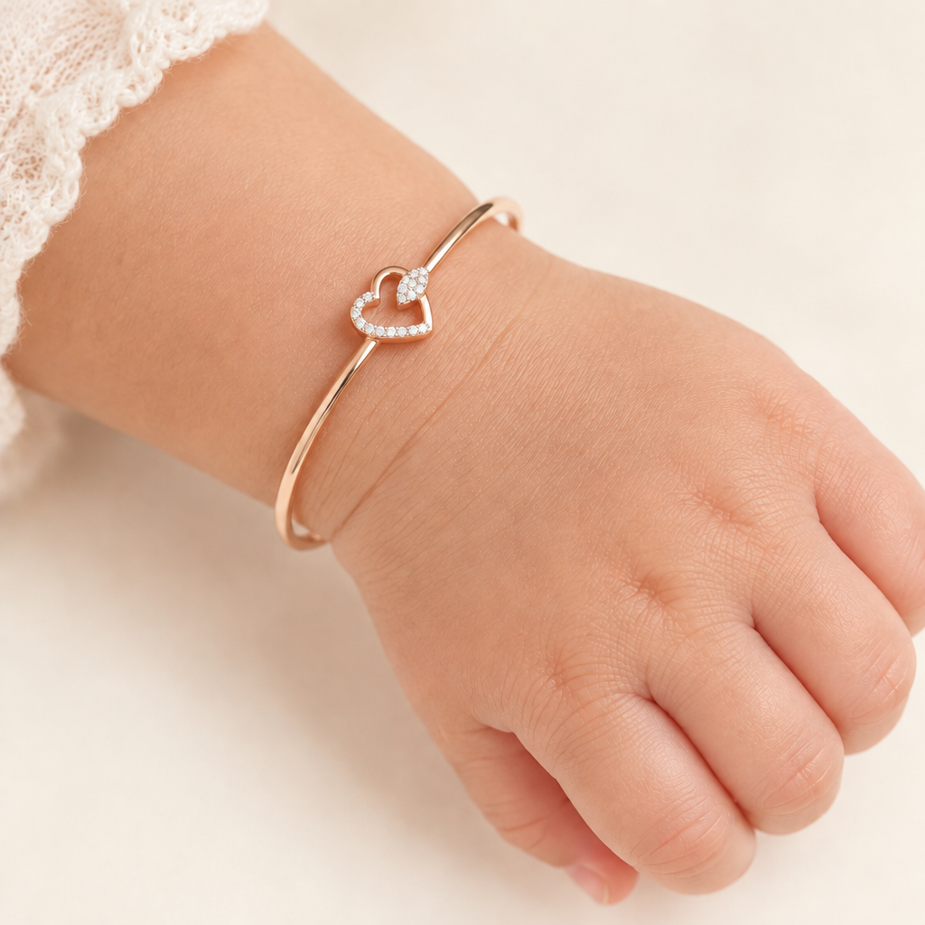 Rose gold bangle-style bracelet with an open diamond heart charm.