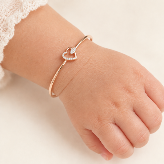 Rose gold bangle-style bracelet with an open diamond heart charm.