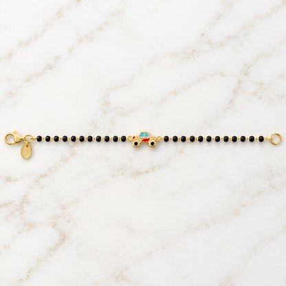 Black bead bracelet with a red and gold race car charm at the center priced under Ra. 30,000