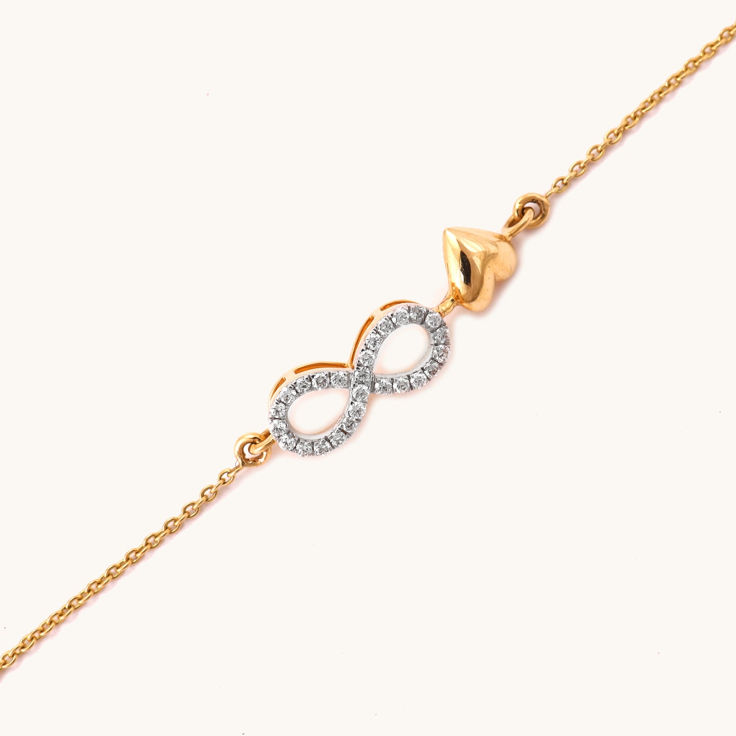 Caratly 18kt gold Infinity Love Bracelet featuring a diamond pave infinity loop intertwined with a small polished solid gold heart charm. Minimal Everyday Wear Gift for her under Rs. 40,000