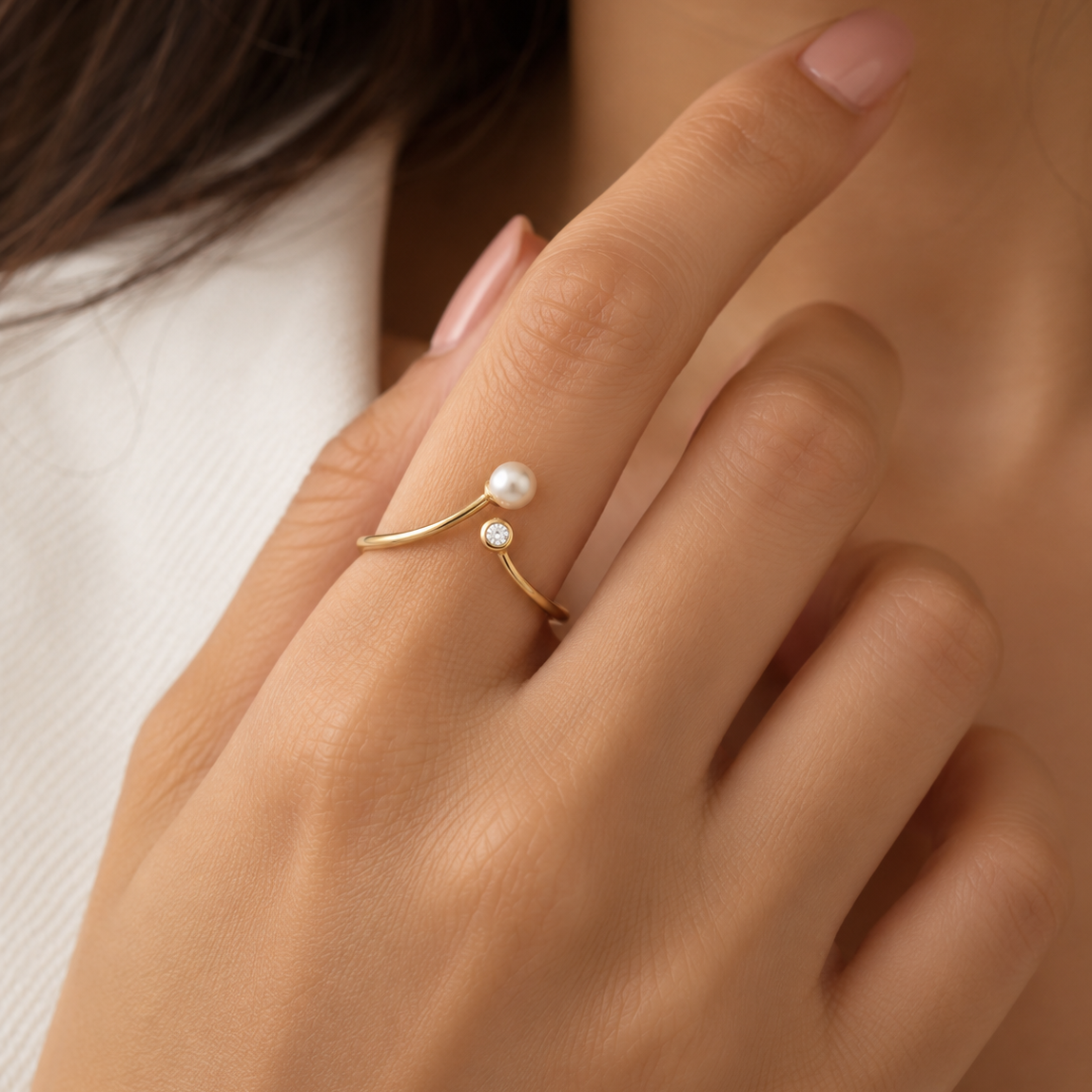 Gold ring with a curved open band, topped with a white pearl and a small diamond under Rs. 20,000