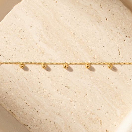 Gold chain bracelet with five small dangling gold ball charms priced under Rs. 60,000