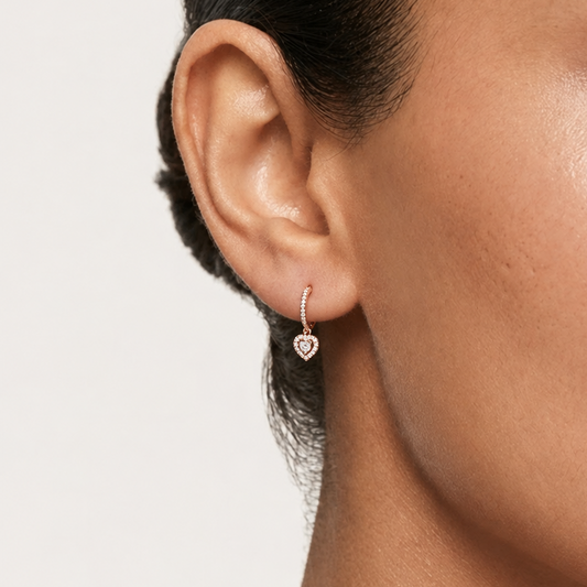 Rose gold huggie hoop earrings with a dangling pave diamond heart charm. Luxe and elegant gifts under Rs. 80,000