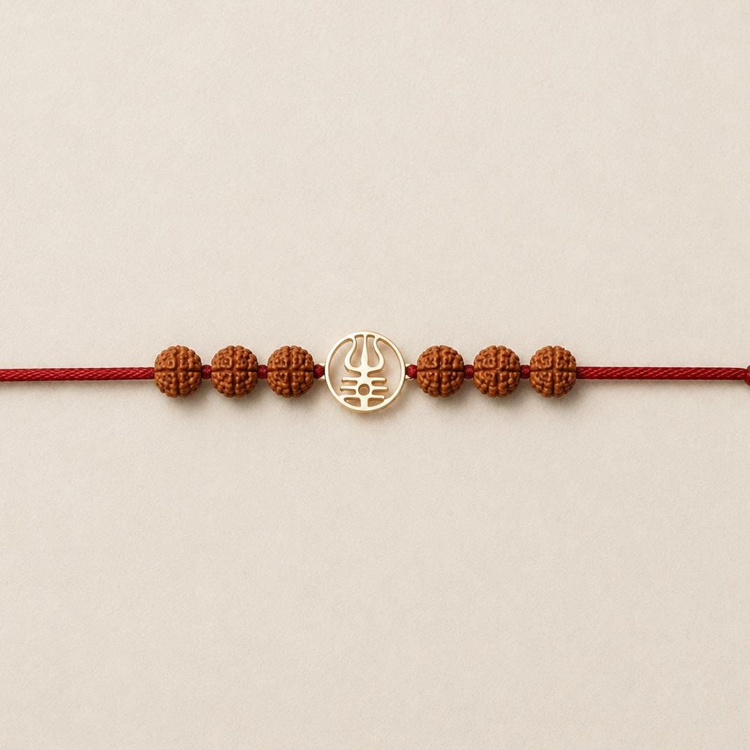 Gold Trishool Rakhi with Rudraksha beads on a wrist.