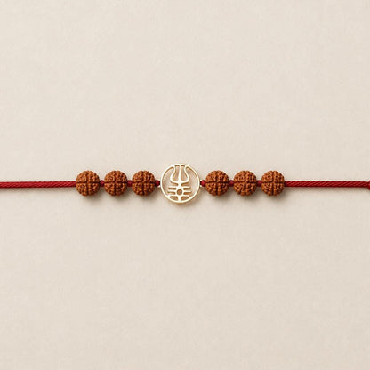 Gold Trishool Rakhi with Rudraksha beads on a wrist.
