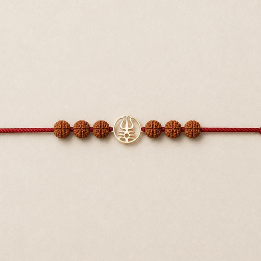 Gold Trishool Rakhi with Rudraksha beads on a wrist.