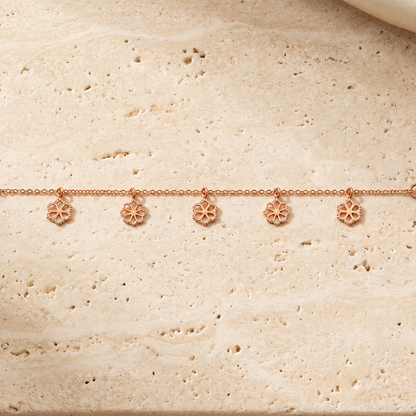Delicate rose gold vertical chain bracelet with small flower and bead station charms priced under Rs. 35,000