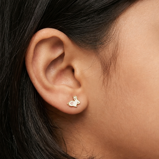 Gold bunny-shaped stud earrings with white enamel and a pink heart detail. A cute gold gift for kids under Rs. 20,000