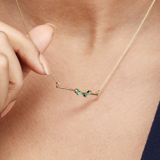 Caratly 18kt gold Baguette Emerald Necklace featuring scattered green baguette-cut emeralds on a horizontal gold bar pendant with attached chain under Rs. 40,000