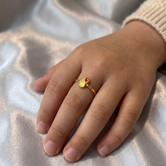 Rose gold ring with a small red and yellow enamel heart-hand charm for newborns priced under Rs. 15,000