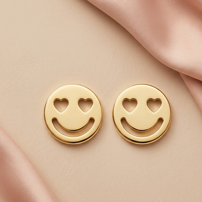 Gold stud earrings shaped like smiley faces with heart-shaped cutout eyes. Minimal gift for her under Rs. 15,000