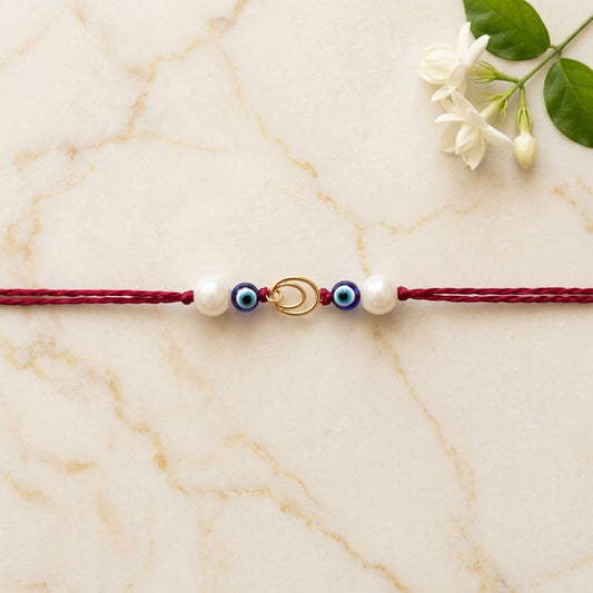 Interlocking gold circle Rakhi with evil eye and pearls.