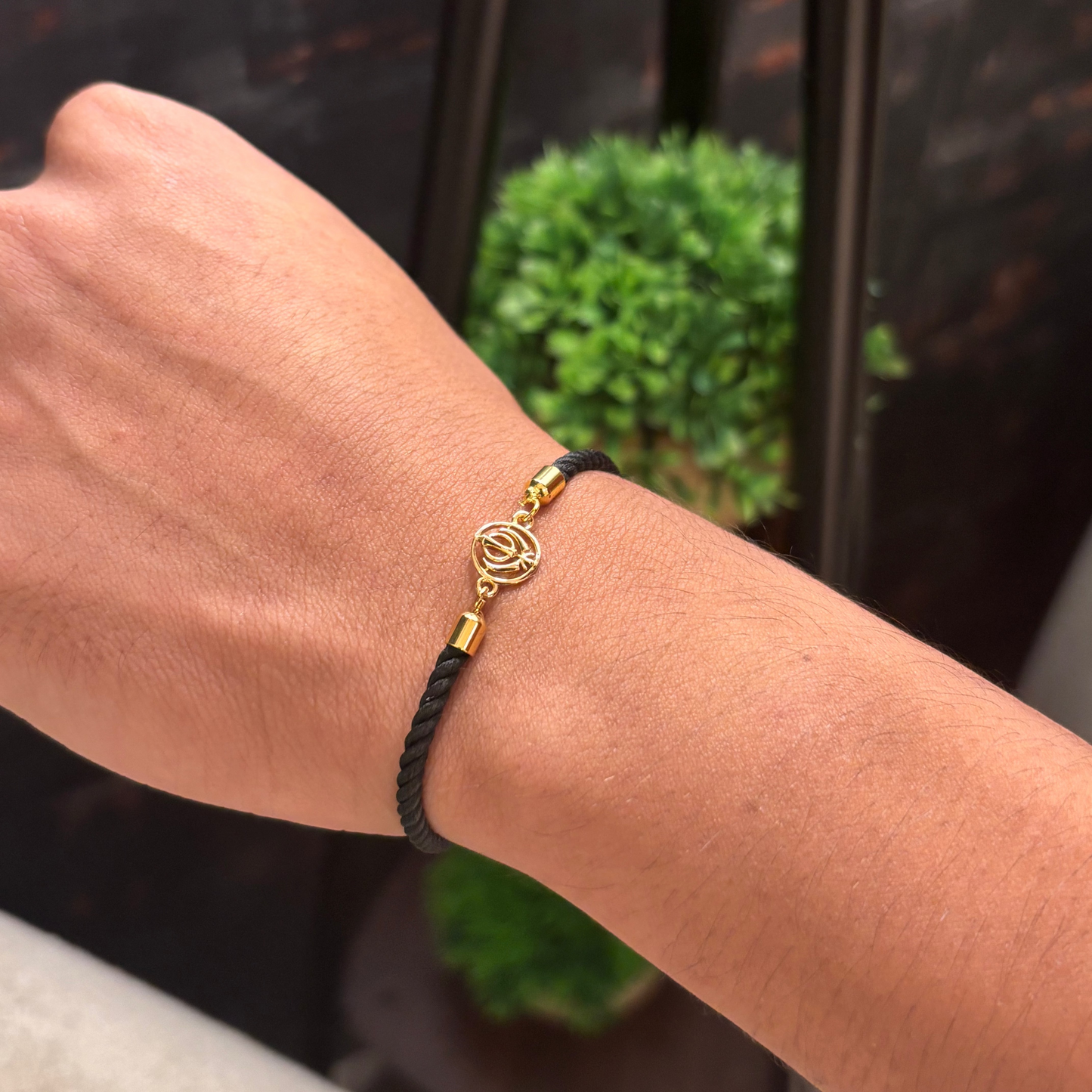 Black rope men's gold bracelet featuring an 18kt gold Khanda symbol charm pendant. A perfect gold gift for him at Rs. 10,000