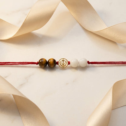Gold Khanda Rakhi with Tiger's eye and white beads.