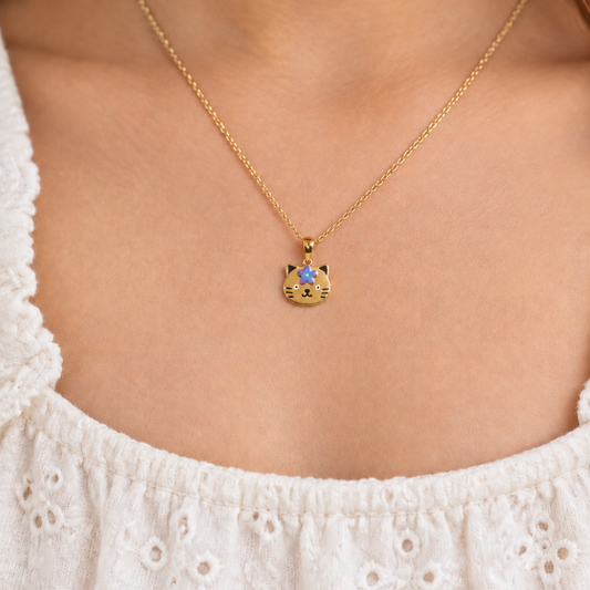 Gold cat-face pendant with a purple enamel flower and black whisker details. Cute gifts for kids under Rs. 50,000