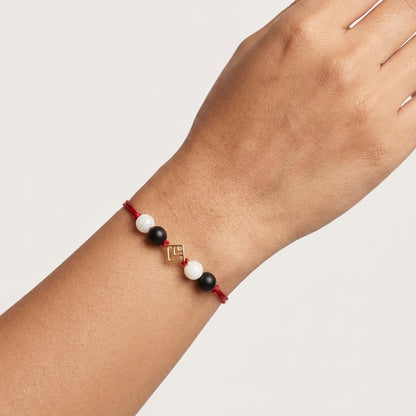 Geometric square gold Rakhi with black and white beads.