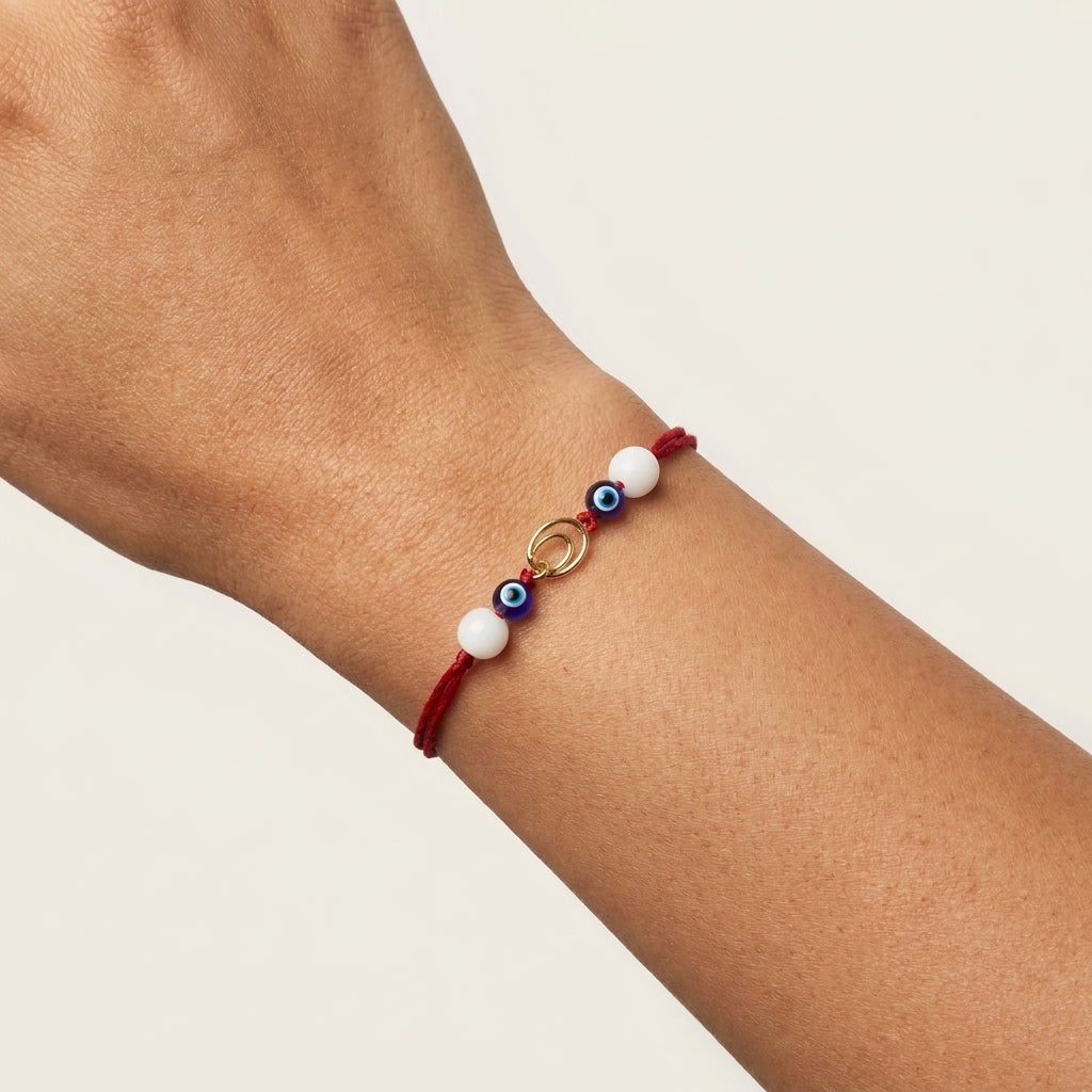Interlocking gold circle Rakhi with evil eye and pearls.