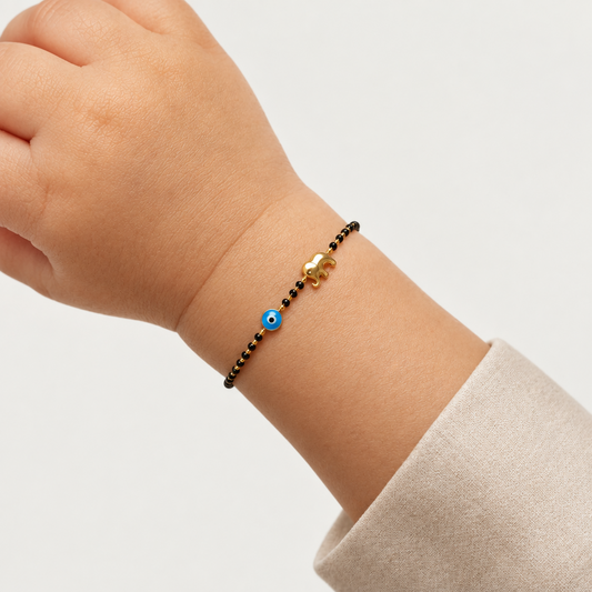 Black bead bracelet with a blue evil eye bead and a gold elephant charm. Minimal and cute gift for kids under Rs. 50,000