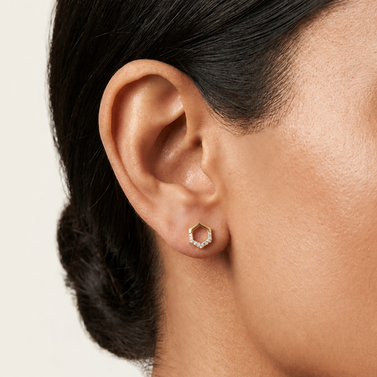 Gold hexagon-outline stud earrings lined with a single row of pave diamonds. Priced under Rs. 30,000