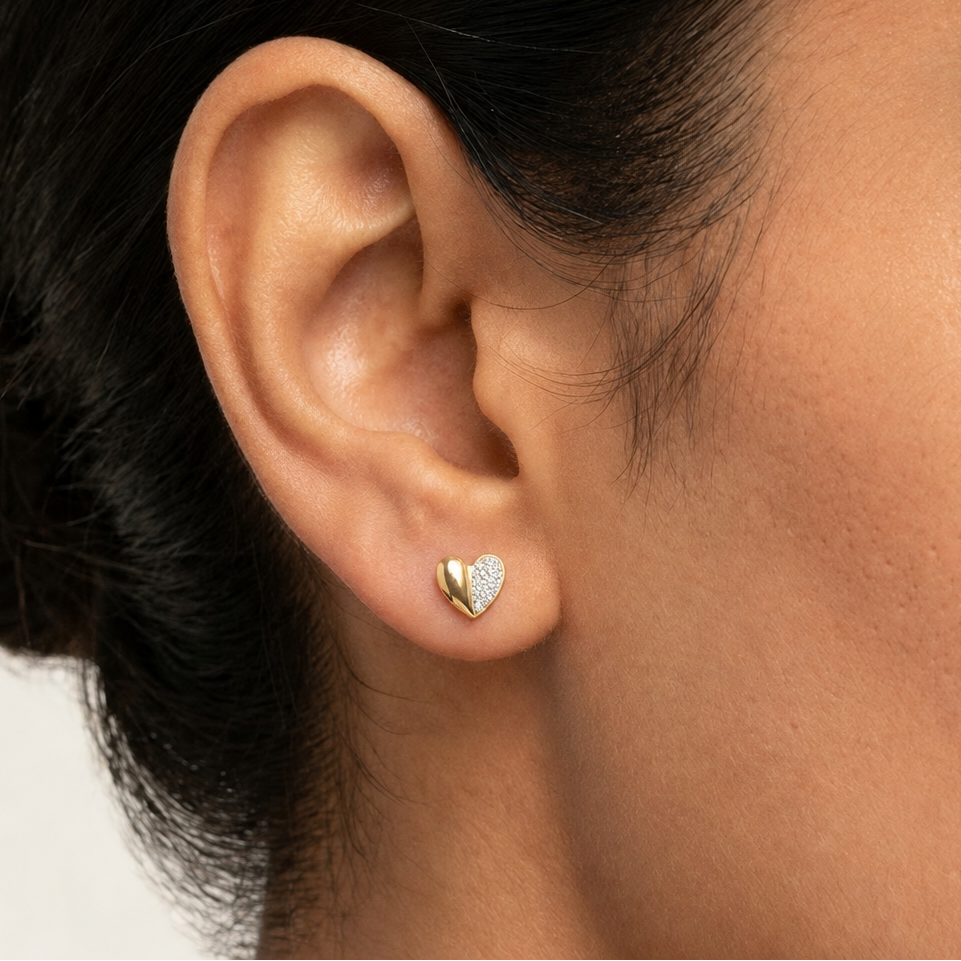 Gold heart-shaped stud earrings, one half polished and one half paved with diamonds. Minimal gifts for her under Rs. 35,000