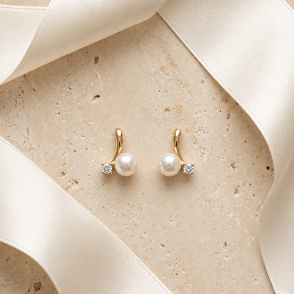 Gold huggie earrings with a white pearl drop and a diamond baguette accent, priced under Rs. 20,000