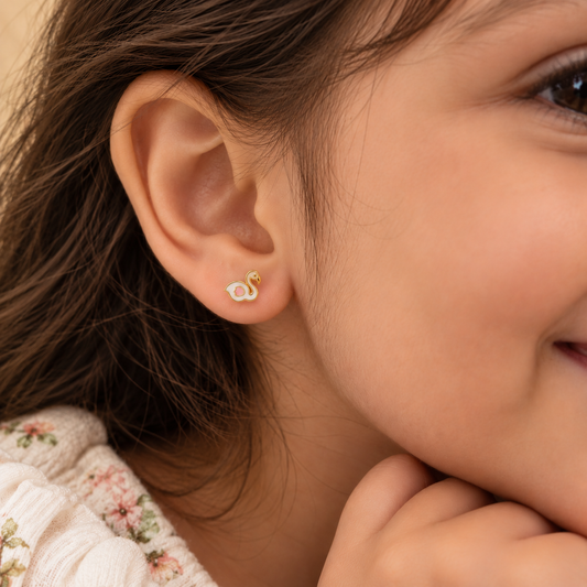 Gold stud earrings shaped like white enamel swans with pink wing detailing. Cute gifts for kids under Rs. 20,000