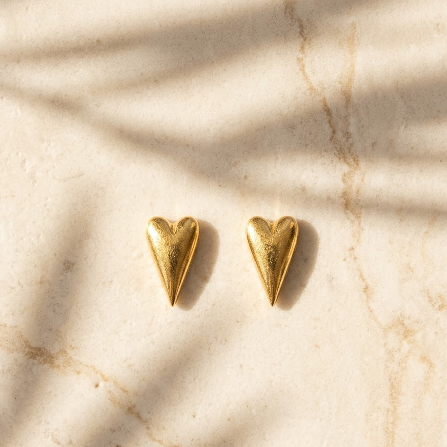 Polished gold heart-shaped stud earrings with a puffed, glossy finish. Minimal and cute gifts for her under Rs. 20,000