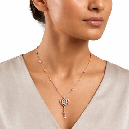 Rose gold heart-shaped pendant with a woven diamond cage design and dangling bead accents. Luxe gifts for her under Rs. 80,000
