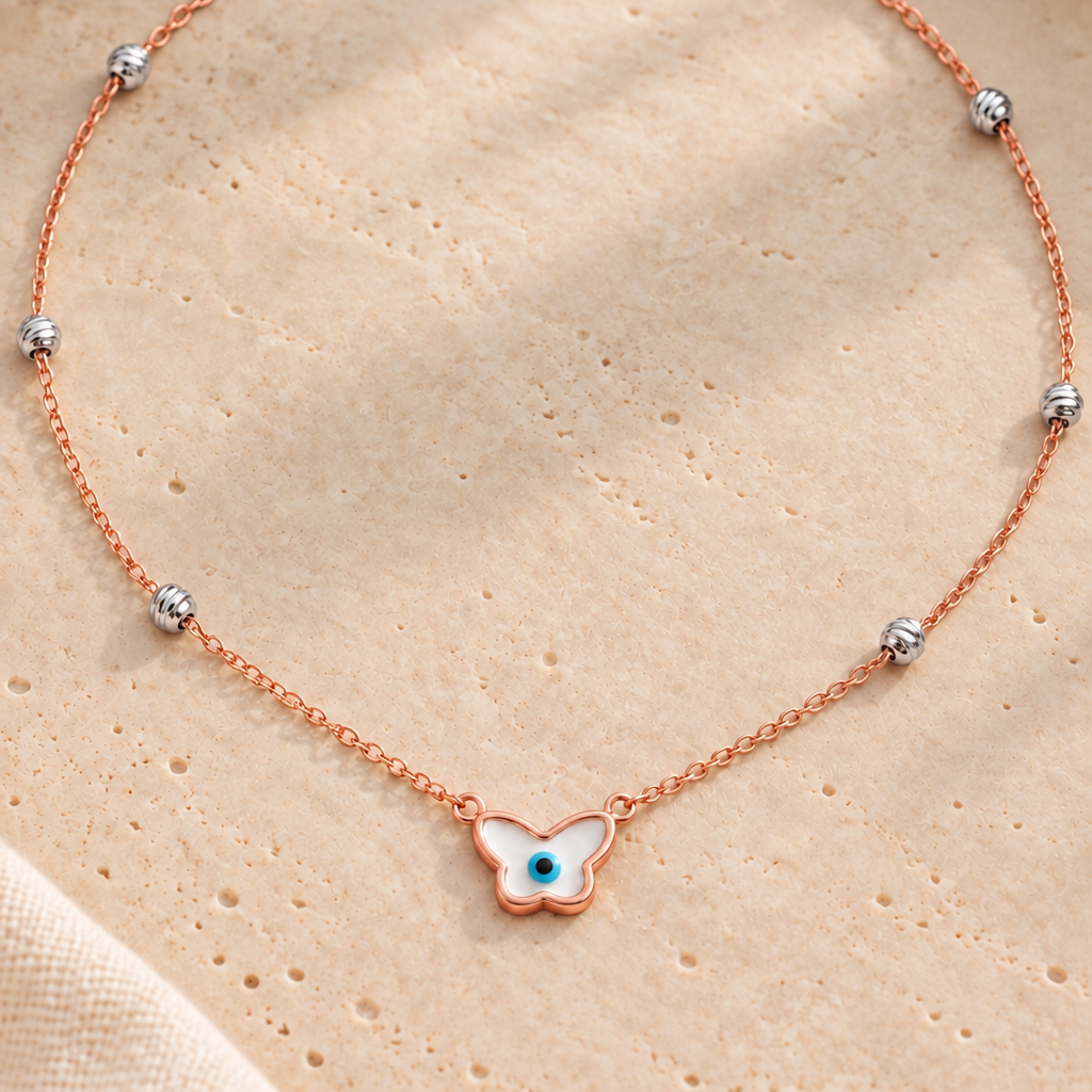 Rose gold chain necklace with a butterfly-shaped evil eye pendant and crystal bead stations. Luxe gifts for her under Rs. 60,000