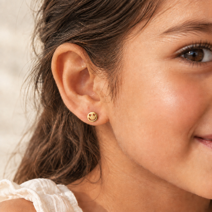 Gold stud earrings shaped like smiley faces with heart-shaped cutout eyes. Minimal gift for her under Rs. 15,000