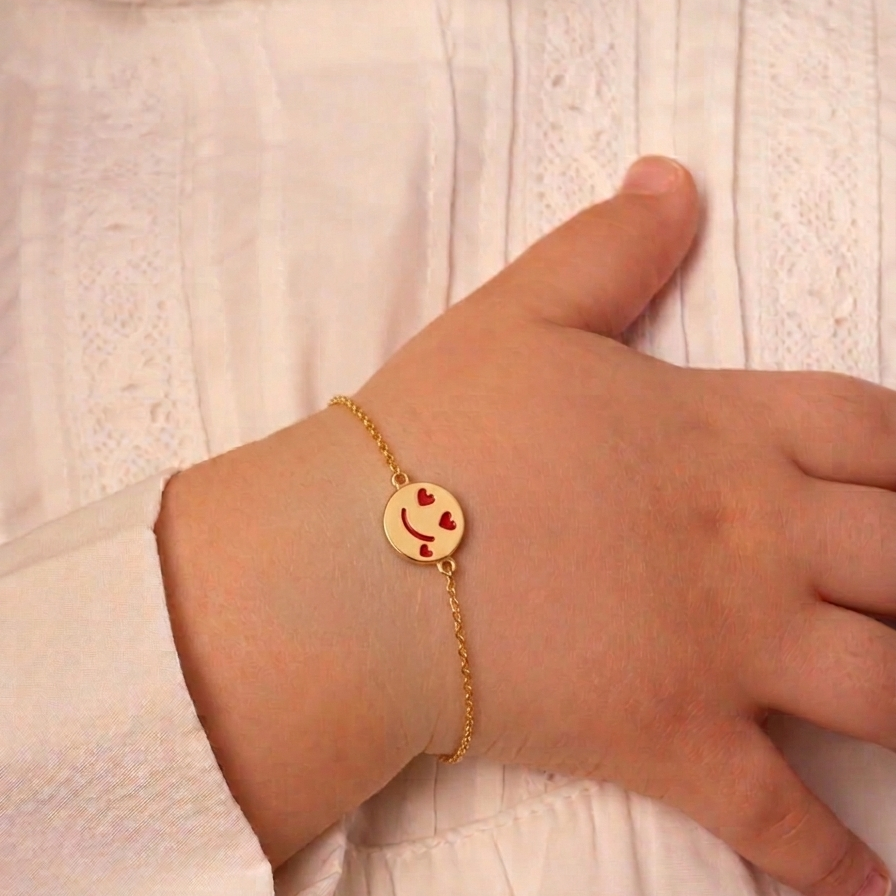 Gold bracelet with a round disc charm featuring a smiley face and red heart eyes. Cute gold gifts for kids under Rs. 40,000
