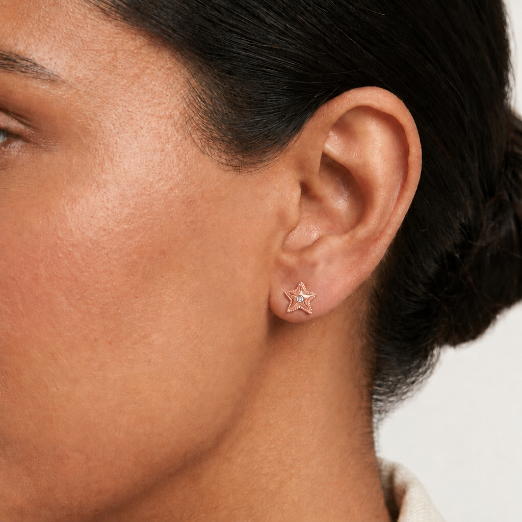 Rose gold textured star stud earrings with a sparkling stone at center. Priced under Rs. 35,000