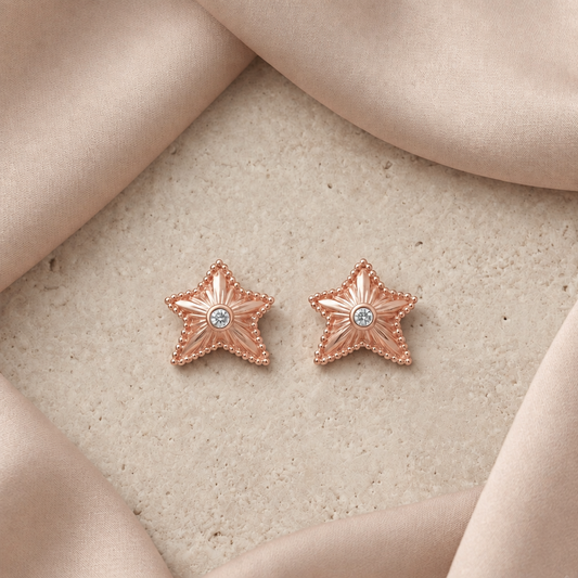 Rose gold textured star stud earrings with a sparkling stone at center. Priced under Rs. 35,000