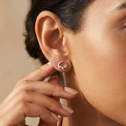 Rose gold circular stud earrings each set with three round diamonds. Priced under Rs. 40,000